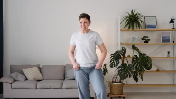 Ανώτερη γυναίκα κάνει διαλογισμό άσκηση τεντώνοντας σπορ γιόγκα. Φωτεινό δωμάτιο στο σπίτι — Αρχείο Βίντεο