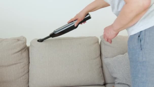 Seniorin staubsaugt Sofa manuellen Staubsauger. Professionelle Putzfrau während der Arbeit — Stockvideo