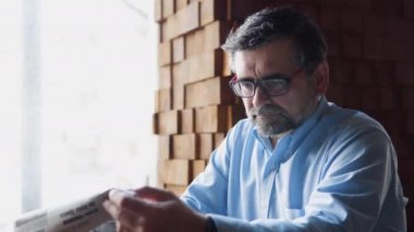 Olgun erkek bir kafede otururken basını okuyor. Emekli dinleniyor.