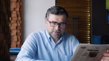 Olgun erkek bir kafede otururken basını okuyor. Emekli dinleniyor.