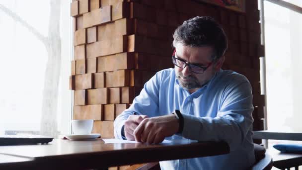 Bir kafede oturan kıdemli adam belgeleri imzalıyor. — Stok video