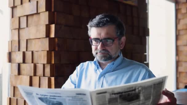 Mature male reads the press while sitting in a cafe. The pensioner is resting — 비디오