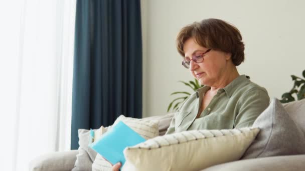 Senior žena čtení literatury příběh na papíře, těší důchod doma — Stock video