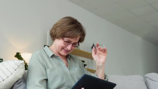 Бабушка-пожилая женщина проводит цифровую планшетную видеоконференцию, разговаривая с врачом или семьей во время виртуального визита на социальную дистанцию в онлайн-чате — стоковое видео