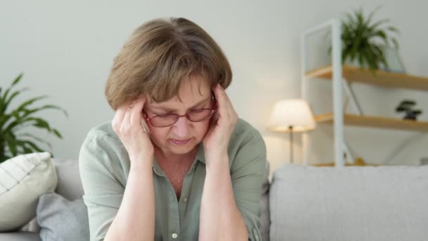 Наголошена старша жінка, яка страждає від хронічного головного болю, стресу вигорання, відчуття мігрені болю, що торкається голови — стокове відео
