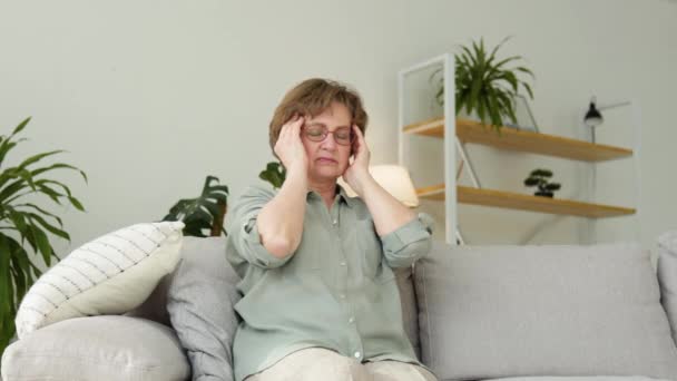 Gestresste oudere vrouw met chronische hoofdpijn, burn-out stress, gevoel van migraine op het hoofd — Stockvideo