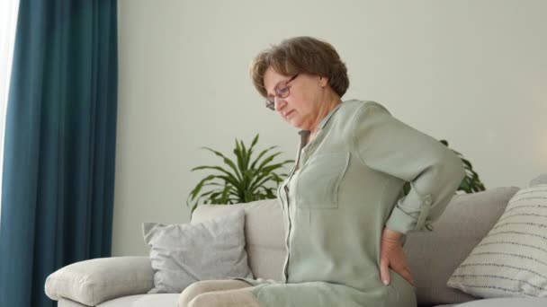 Reife Frau sitzt auf dem Bett und berührt Rücken, Radikulitis und Schmerzen — Stockvideo