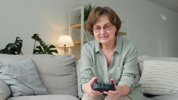 Vista frontale della donna anziana che gioca al videogioco e utilizza il joystick — Video Stock