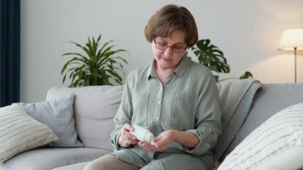 Mujer adulta mayor sosteniendo píldoras analgésicas en cápsulas de mano femenina vertiendo de botella médica — Vídeos de Stock