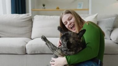 Mutlu genç kız güneşli oturma odasında bir köpekle oynaşıyor. Mutlu evcil hayvan konsepti, en iyi arkadaşlar