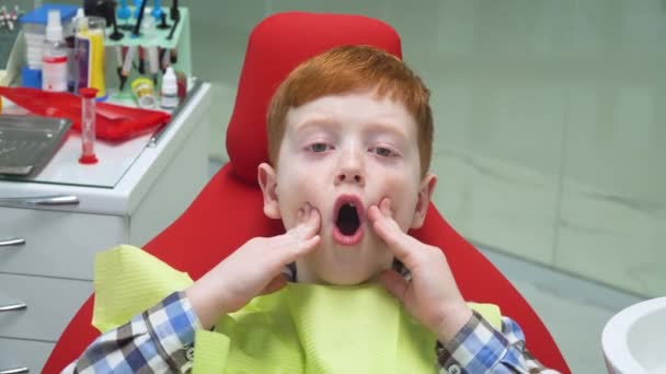 Rädd pojke i receptionen hos tandläkaren i tandläkarstolen. Pediatrisk tandvård — Stockvideo