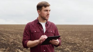 Farmer on a field with a tablet before planting agricultural cultures