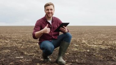 Çekici çiftçinin tarladaki portresi, kameraya neşeyle gülümseyen ve baş parmağını veren. Yazın açık havada gülümseyen çiftçi