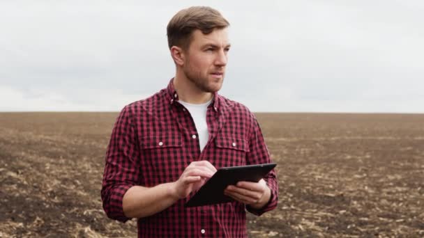 Farmer on a field with a tablet before planting agricultural cultures — Video Stock