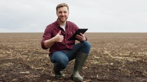 Portrait shot of attractive farmer in field, smiling cheerfully to camera and giving thumb up. Farmer with smile outdoors in summer — Video