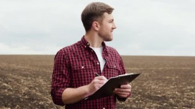 Farmer on a field with notebook before planting agricultural cultures