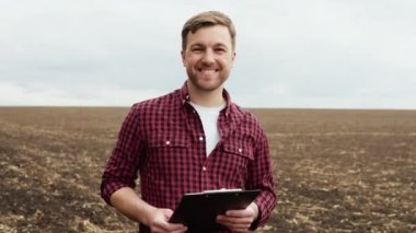 Tarımsal kültürleri ekmeden önce elinde defterle tarlada çiftçi.