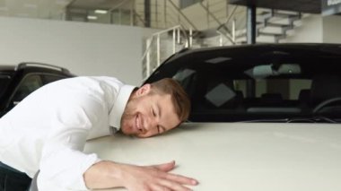 Mutlu bir adam yeni arabasına sarıldı, nazikçe gülümsedi.