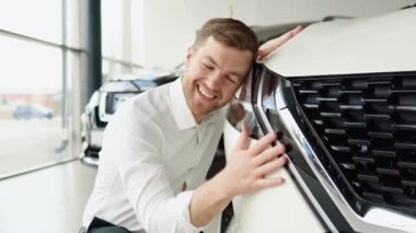 Mutlu bir adam yeni arabasına sarıldı, nazikçe gülümsedi.