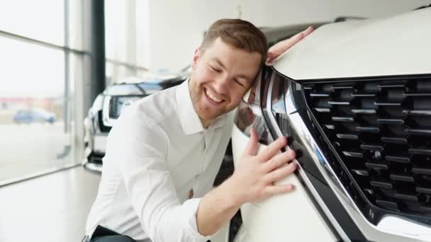 Een gelukkige man omhelst zijn nieuwe auto, glimlachend zachtjes — Stockvideo