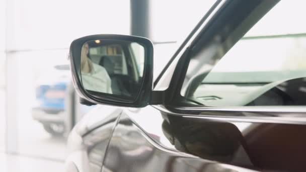 Dobrando o espelho retrovisor exterior com built-in luz de sinal de volta em um carro elétrico marrom de prestígio em um showroom revendedor — Vídeo de Stock