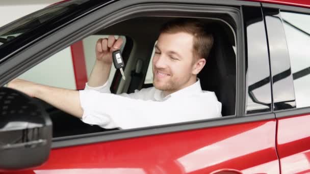 Mężczyzna z kluczami pokazuje emocje szczęścia podczas jazdy jej nowym elektrycznym samochodem. Kupujący wybiera samochód. — Wideo stockowe