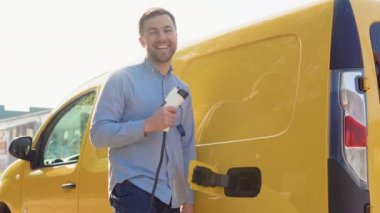 A happy man with a charger at a charging station