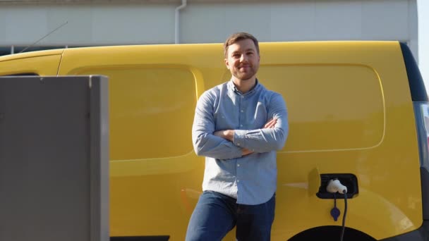 Un uomo che collega auto elettrica mini van alla stazione di ricarica elettrica auto elettrica ricarica uomo rispettoso dell'ambiente ricarica il suo veicolo elettrico — Video Stock