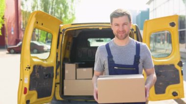 Paket tutan bir kuryenin portresi, arka planda sarı bir araba. Teslimat konsepti: Mavi üniformalı kurye.