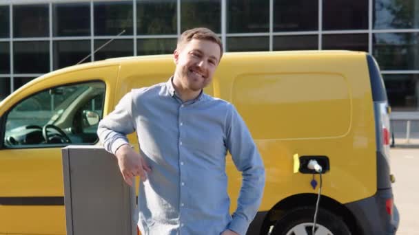 Happy man charges an electric car at a charging station. Concept of green energy — Video Stock