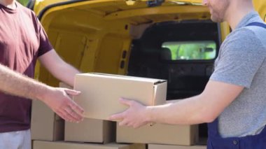 Genç postacı, güvenli bir şekilde eve bir paket teslim ediyor. Kurye konsepti, ev teslimatı, e-ticaret nakliyesi, virüs, covid