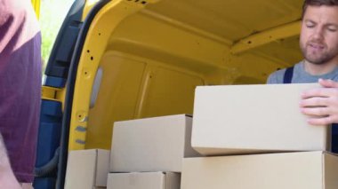 Genç postacı, güvenli bir şekilde eve bir paket teslim ediyor. Kurye konsepti, ev teslimatı, e-ticaret nakliyesi, virüs, covid