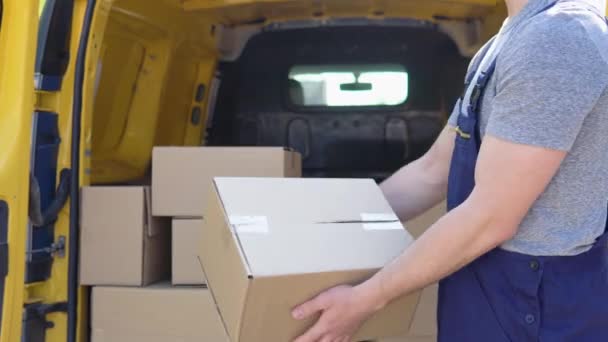 Cheerful courier throws the parcel standing near delivery van — Stockvideo