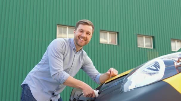 Muž zapojující dodávku s elektromobilem na dobíjecí stanici elektrický vůz dobíjí ekologicky uvědomělý muž nabíjející své elektrické vozidlo — Stock video