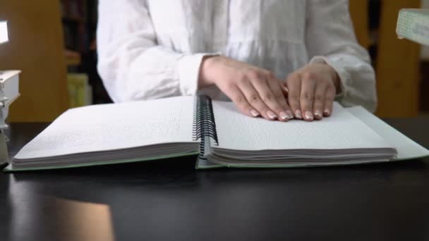 Blind meisje leest een tekst van braille in de bibliotheek. Hand raakt de beschrijving in braille. — Stockvideo