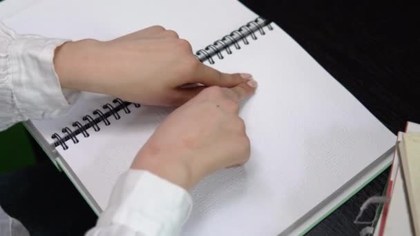 Female student studying in a library, sitting and reading a braille book — Stok video