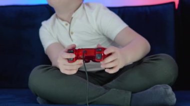 Çocuk video oyunu oynamak için kumanda kullanıyor. Karanlık bir odada bir eSports oyun turnuvasında bilgisayar oyunu oynayan bir kontrolörde eller.