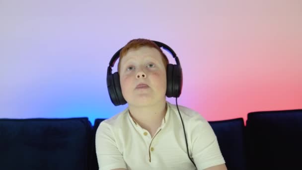 Közelkép portré egy kisfiú játszik online számítógépes videojáték este otthon. Gamer megvitatása taktika csapattársak, miközben beszél headset — Stock videók