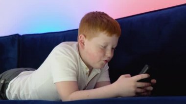 Çocuk video oyunu oynamak için eski kumandayı kullanıyor. Bir çocuk eski 8 bit oyununu oynuyor. Sıcak ve neon ışıklı rahat bir oda.