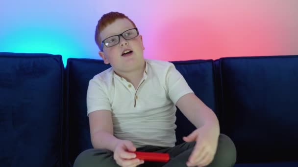 Dreng bruger gamle controller til at spille videospil. En dreng spiller 8 bit spil. Hyggeligt værelse med varmt og neonlys – Stock-video
