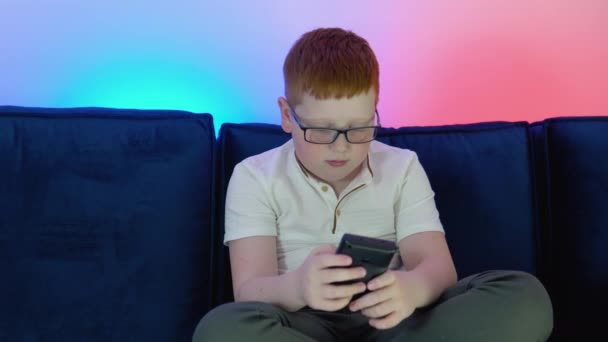 Boy uses old controller to play video game. A boy plays old 8 bit game. Cozy room with warm and neon light — 图库视频影像