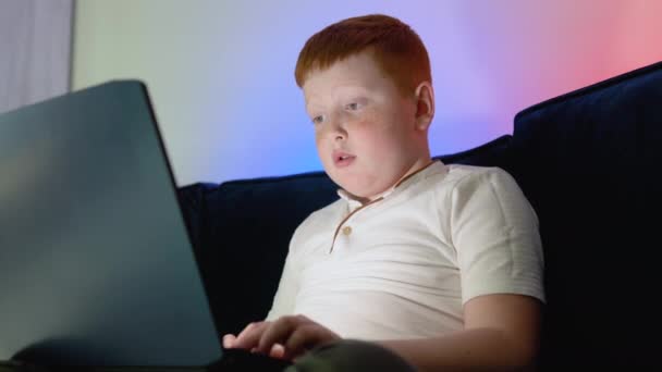 Computer verslaafde tiener jongen kijkt naar het notebook scherm op het toetsenbord. Tiener met behulp van laptop 's nachts tijd — Stockvideo