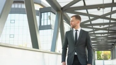 Kendine güvenen çekici iş adamı büyük bir ofis binasının yakınına gidip etrafa bakıyor.