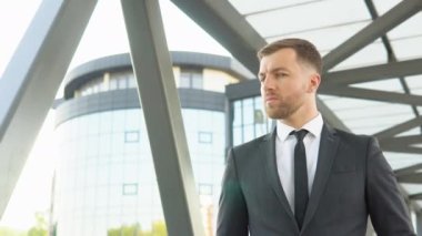 Modern ticari kompleksin dışındaki kameraya bakan yakışıklı bir işadamı.