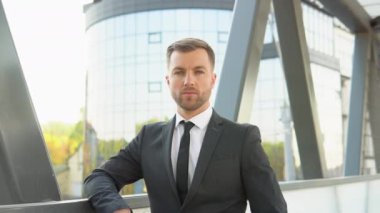 Modern ticari kompleksin dışındaki kameraya bakan yakışıklı bir işadamı.