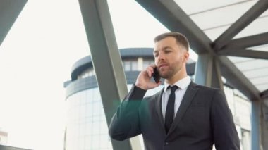 Happy businessman learns good news from business partner. Portrait of happy business man calling phone outdoor