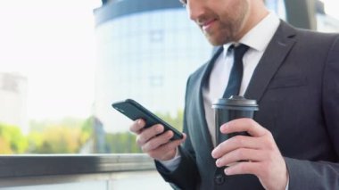 İş merkezinin yakınında cep telefonu kullanan kendine güvenen genç bir işadamı.