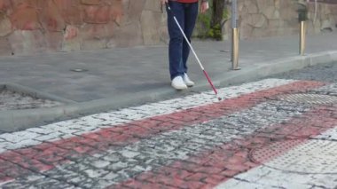 Dışarıda tek başına yürümek için güvenlik çubuğu kullanan genç kör bir adam. Bastonlu kör bir adam karşıya geçiyor.