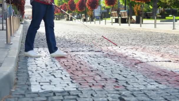 En blind man med käpp korsar vägen. Ung blind man med säkerhetpinne för promenader ensam utomhus — Stockvideo