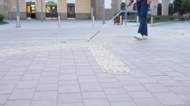 Dışarıda tek başına yürümek için güvenlik çubuğu kullanan genç kör bir adam. Gözlük takan ve günlük kıyafetler giyen bir erkek. Bağımsızlık kavramı